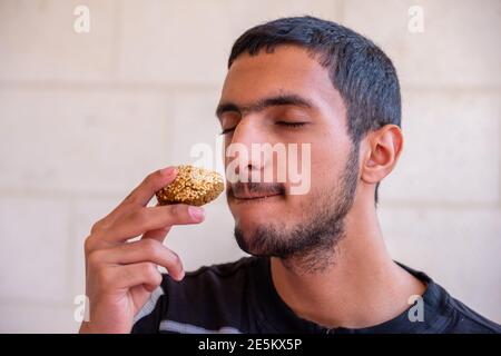 L'uomo musulmano sta mangiando falafel e godendo il suo tempo Foto Stock
