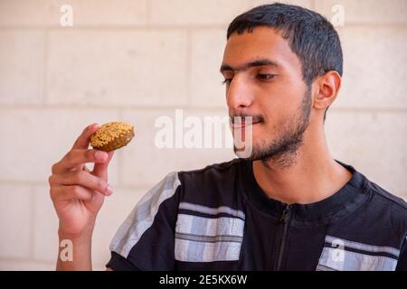 L'uomo musulmano sta mangiando falafel e godendo il suo tempo Foto Stock