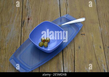 Kit di plastica per servire olive blu su vecchio sfondo di legno con olive e forchetta, Brasile, Sud America Foto Stock