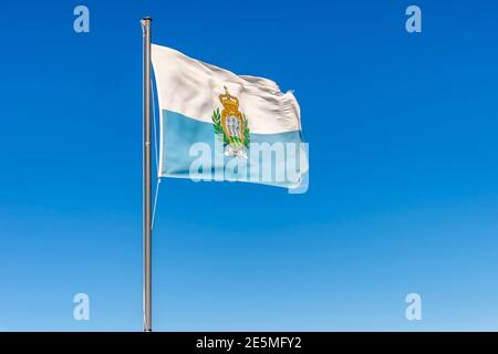 La bandiera nazionale della Repubblica di San Marino svanita nel vento contro il cielo blu Foto Stock