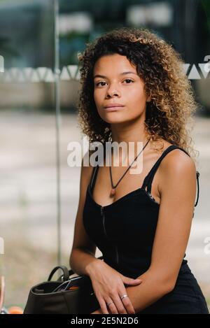 Bella giovane donna in attesa alla stazione degli autobus in città Foto Stock