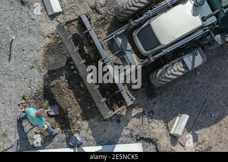 Il lavoratore carica il terreno nella benna dell'escavatore durante la costruzione di strade e. riparare Foto Stock
