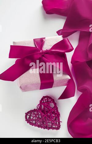 Concetto di design di San Valentino - confezione regalo e cuore su sfondo bianco, foto verticale Foto Stock