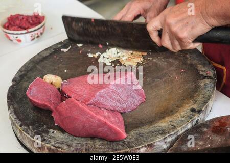 Una donna che taglia carne di manzo incontra e zenzero su tavola di legno. Primo piano. Foto Stock