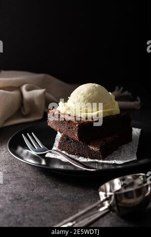 Brownie con scoop gelato alla vaniglia su sfondo nero Foto Stock