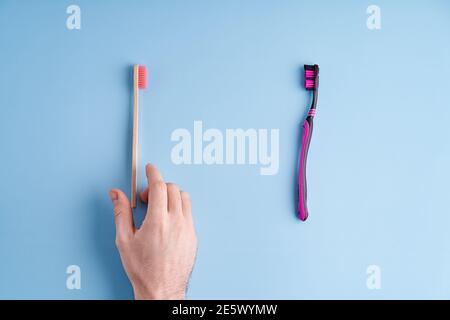 Scegliete tra uno spazzolino in plastica e uno spazzolino in bambù ecologico. Tendenze ecologiche a livello mondiale. Foto Stock