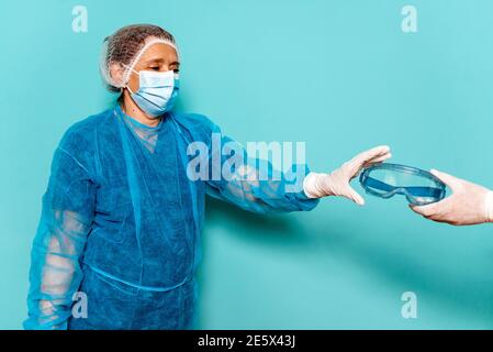 Foto di scorta di operatori sanitari professionisti che indossano speciali indumenti monouso e occhiali protettivi per covid19. Foto Stock