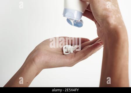 Donna che tiene il tubo della crema e che applica la crema idratante sulle sue mani belle. Foto Stock