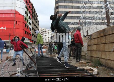 Tripoli. 28 Gennaio 2021. Le persone gettano pietre nell'edificio governativo del governatorato durante una protesta a Tripoli, Libano, il 28 gennaio 2021. Giovedì a Tripoli è scoppiato un nuovo round di scontri tra forze di sicurezza e manifestanti contro il blocco totale imposto dalle autorità per frenare il COVID-19, i media locali hanno riferito. Credit: Khaled/Xinhua/Alamy Live News Foto Stock