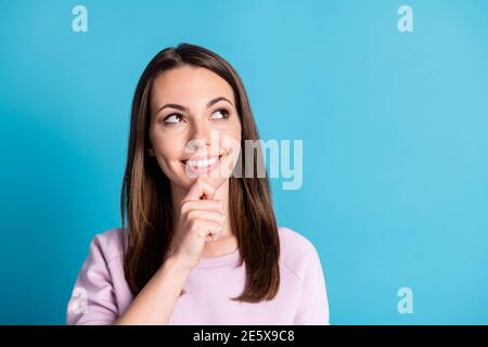 Foto di simpatica giovane signora che si inonita sorridendo mento dito sognare immaginare cercare spazio vuoto fantastico data ragazzo vicino indossare un pullover viola Foto Stock