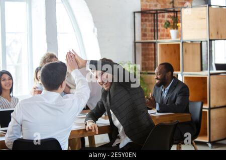 Lavoro di squadra. Gruppo diversificato di collaboratori che hanno una discussione informale in ufficio. Dirigenti durante discussioni amichevoli, rapporti mensili, incontri creativi. Concetto di business, finanza, occupazione, lavoro. Foto Stock