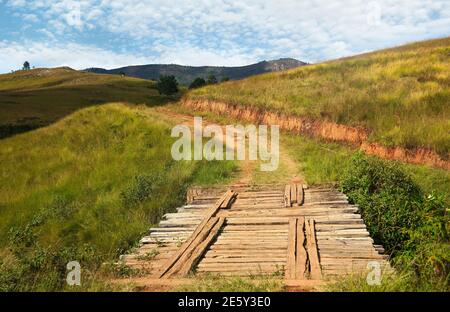 Ponte fatto di barre di legno su strada di campagna, erba che cresce su entrambi i lati colline - vista tipica durante la guida fuoristrada 4x4 veicolo vicino Andringitra parco, Foto Stock