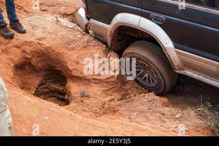 veicolo 4wd che guida su strada con fori e dossi estremi, primo piano sulla ruota posteriore - le strade sono in condizioni molto cattive in Andringitra, Madagascar, espe Foto Stock