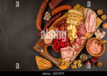 Vari tipi di salame, speck e salsicce su un tavolo di legno. Cibo spazzatura grasso. Carne affumicata. Concetto di obesità. Sovrappeso. Foto Stock