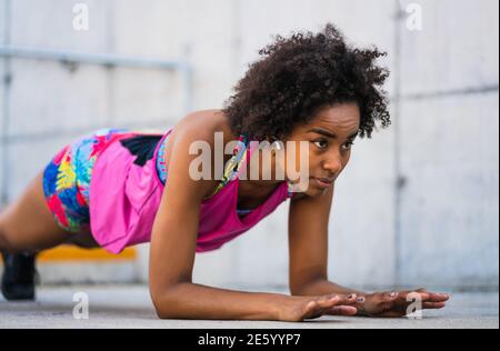 Donna afro atleta che fa pushup all'aperto. Foto Stock