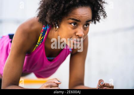 Donna afro atleta che fa pushup all'aperto. Foto Stock