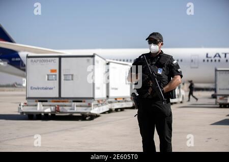 La guardia di sicurezza armata presso l'aeroporto di Santiago protegge lo sbarco della prima spedizione di quasi 2 milioni di dosi del vaccino Sinovac contro il Covid-19 da Pechino, ChinaLa pandemia in Cile ha causato la morte di più di 18,000 persone nell'ultimo anno, il paese è ancora sotto un coprifuoco e alcune città in totale quarantena. Foto Stock