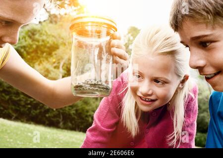 Giovani ragazzi e una ragazza guardando il serpente nel vasetto esterno Foto Stock