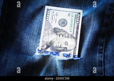 Cento dollari in jeans blu strappati. Povertà e ricchezza in abiti lacerati. Furto di fondi di bilancio, corruzione, furto Foto Stock