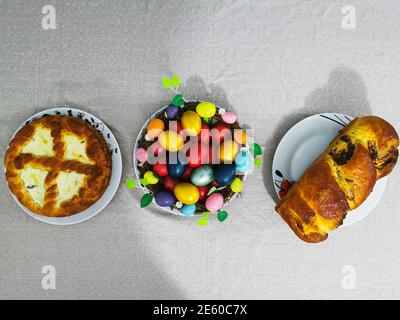 Immagine dei piatti tradizionali della cena pasquale come uova colorate, torta al formaggio e panettone Foto Stock