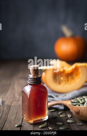 Olio di semi di zucca pressato a freddo in una bottiglia di vetro, decorato con semi sbucciati su un tavolo di legno con spazio per la copia Foto Stock