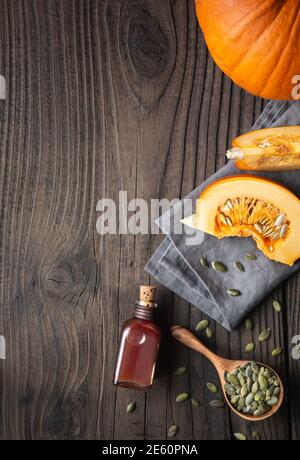 Olio di semi di zucca pressato a freddo in una bottiglia di vetro, decorato con semi sbucciati su un tavolo di legno con spazio per la copia Foto Stock