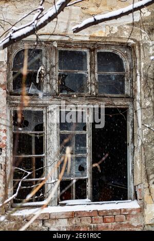 Primo piano di una finestra di vetro rotta su una vecchia casa infestata e apocalittica Foto Stock