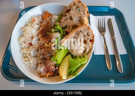 Delizioso e appetitoso pesce rosso alla griglia, pane fatto in casa, riso e insalata serviti in un vassoio con forchetta e coltello, dettagli, primo piano Foto Stock