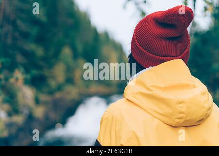 Uno con la natura. Vista posteriore di una donna irriconoscibile che guarda alla foresta e alla cascata Foto Stock