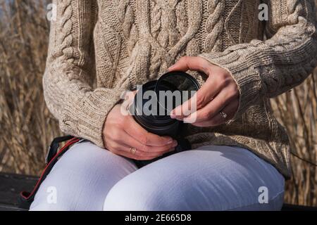 Una donna che posiziona un filtro dell'obiettivo su una fotocamera mentre seduto all'esterno Foto Stock