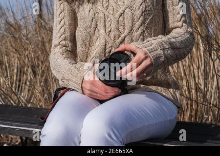 Una donna che posiziona un filtro dell'obiettivo su una fotocamera mentre seduto all'esterno Foto Stock
