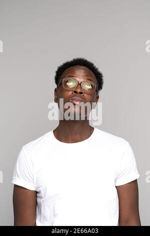 L'uomo afroamericano in occhiali indossa una t-shirt bianca pensando, guardando in su lo spazio di copia, isolato Foto Stock