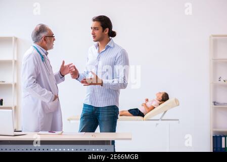 Bambina con il padre che visita il medico maschile anziano Foto Stock