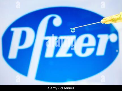 Vienna Austria 28 gennaio 2021, siringa con gocce di liquido contro il logo Pfizer una multinazionale americana farmaceutica vaccino Coronavirus Foto Stock