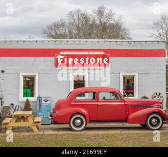 auto del 1940 vicino ad un vecchio edificio con un firestone segno Foto Stock