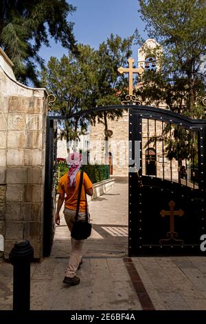 Una persona araba che indossa Keffiyeh Giordano sta entrando nella storica chiesa bizantina di San Giorgio a Madaba, Giordania. Questa antica chiesa ha la f Foto Stock