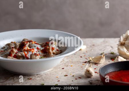 Il tradizionale manti Turco è una forma di gnocchi fatti con carne macinata e servita in aglio yogurt e salsa di pomodoro condito con peperoni rossi tritati a Foto Stock