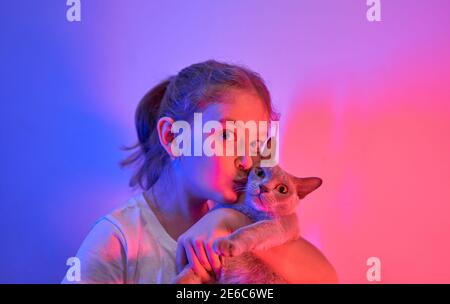 La bambina caucasica tiene il suo gatto tra le braccia Foto Stock