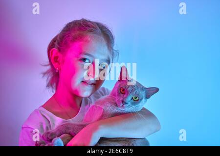 La bambina caucasica tiene il suo gatto tra le braccia Foto Stock