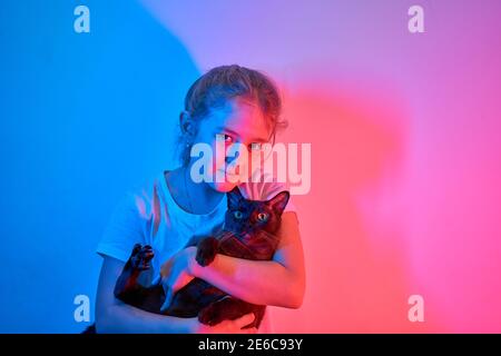 La bambina caucasica tiene il suo gatto tra le braccia Foto Stock