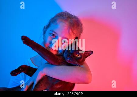 La bambina caucasica tiene il suo gatto tra le braccia Foto Stock