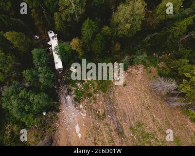 Vista dall'alto aerea carro di camion abbandonato tra gli alberi è caduto fuori strada Foto Stock