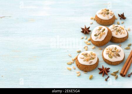 Pan di zenzero di Natale al miele profumato con smalto, noci e semi su sfondo azzurro con spezie, spazio libero, primo piano, orizzontale Foto Stock