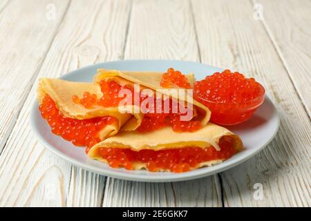 Piatto di crepes con caviale rosso su sfondo bianco di legno Foto Stock