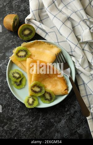 Concetto di deliziosa colazione con crepes con kiwi su nero sfondo smussato Foto Stock