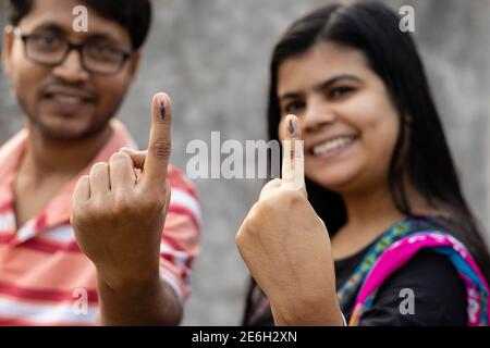 L'uomo e la donna indiani mostrano le dita marcate con inchiostro con volti sorridenti dopo la votazione Foto Stock