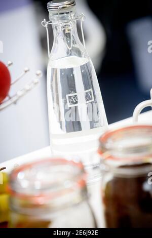 Una moderna cucina da ufficio con una bottiglia d'acqua di vetro posta su un piano di lavoro bianco con uno sfondo fuori fuoco. Foto Stock