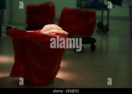 Guanti chirurgici usati sulla spazzatura rossa sotto lampada chirurgica Foto Stock