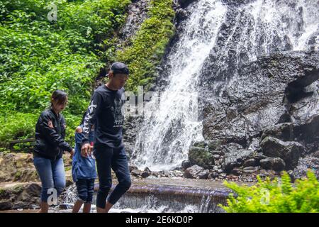 Città di Batu, Indonesia. Novembre 2020. La famiglia sta godendo la freschezza della cascata Watu Lumpang. Genitori e bambini sono in vacanza in fresco Foto Stock