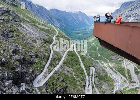 I turisti sul punto panoramico Trolls Point ammirando la montagna Trollstigen passa e il bellissimo paesaggio sotto e intorno a loro - Viaggiare in Norvegia Foto Stock